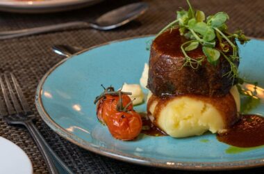 Luxurious beef dish with mashed potato and cherry tomatoes at upscale hotel restaurant.