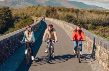 Guests cycling on a scenic path with lush greenery and mountain views, enjoying outdoor adventure and nature at the hotel.