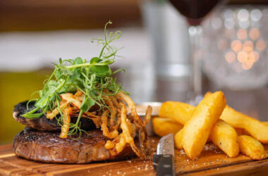 Sizzling steak with crispy chips and garnish in elegant hotel restaurant.