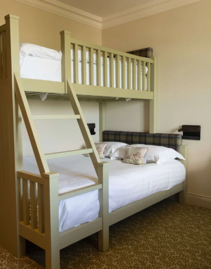 Family-friendly hotel room with bunk beds, plush carpet, and cosy lighting, perfect for a comfortable, fun stay.