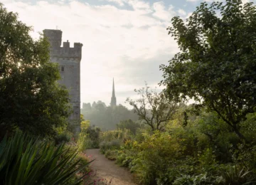 Lush garden view with historic castle tower and distant spire