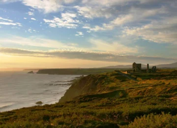 Breathtaking coastal view with ocean cliffs at sunset, perfect for a serene hotel getaway near historical ruins.
