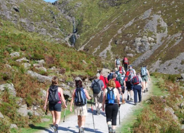 Guests hiking scenic trail amidst lush hills near cosy hotel, perfect for outdoor enthusiasts and nature lovers.
